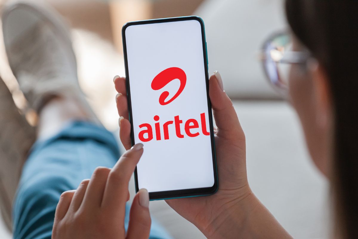 Person holding smartphone with Airtel logo on screen.