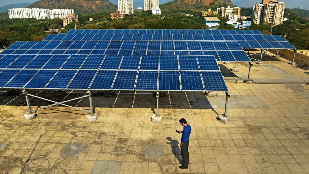 Solar panels on building rooftop with person inspecting.