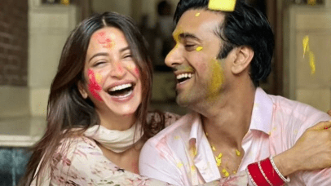 Couple laughing with colorful Holi festival paint on faces.