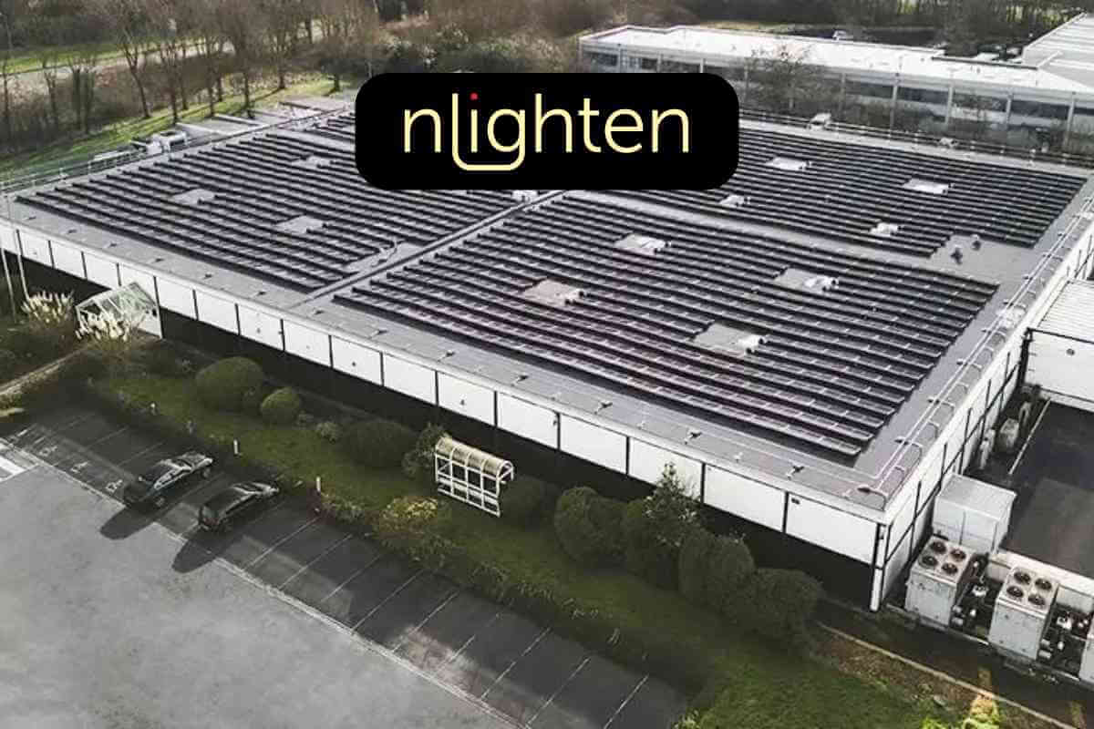 Industrial building with solar panel roof and parking lot.