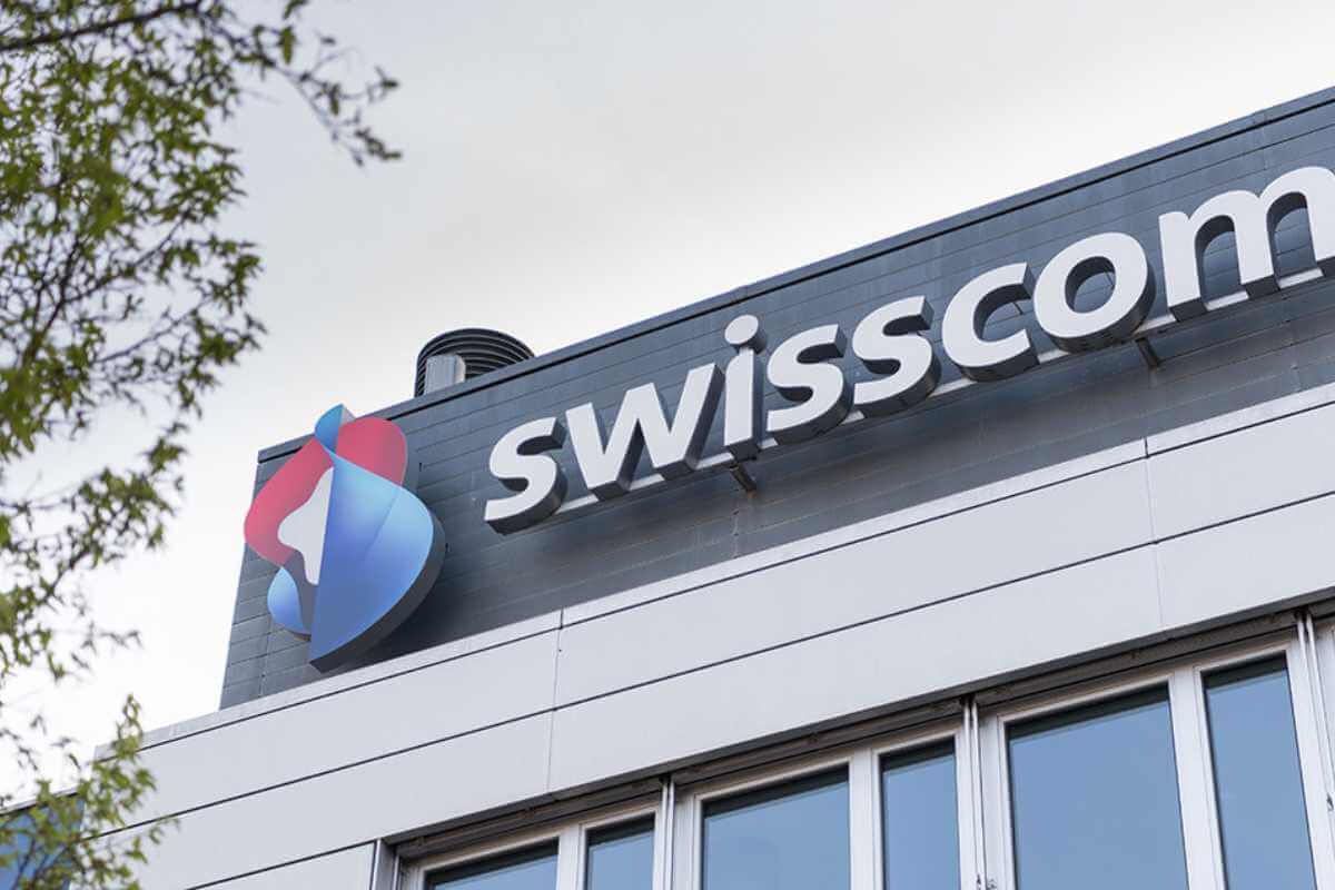 Swisscom logo on building facade with tree branch