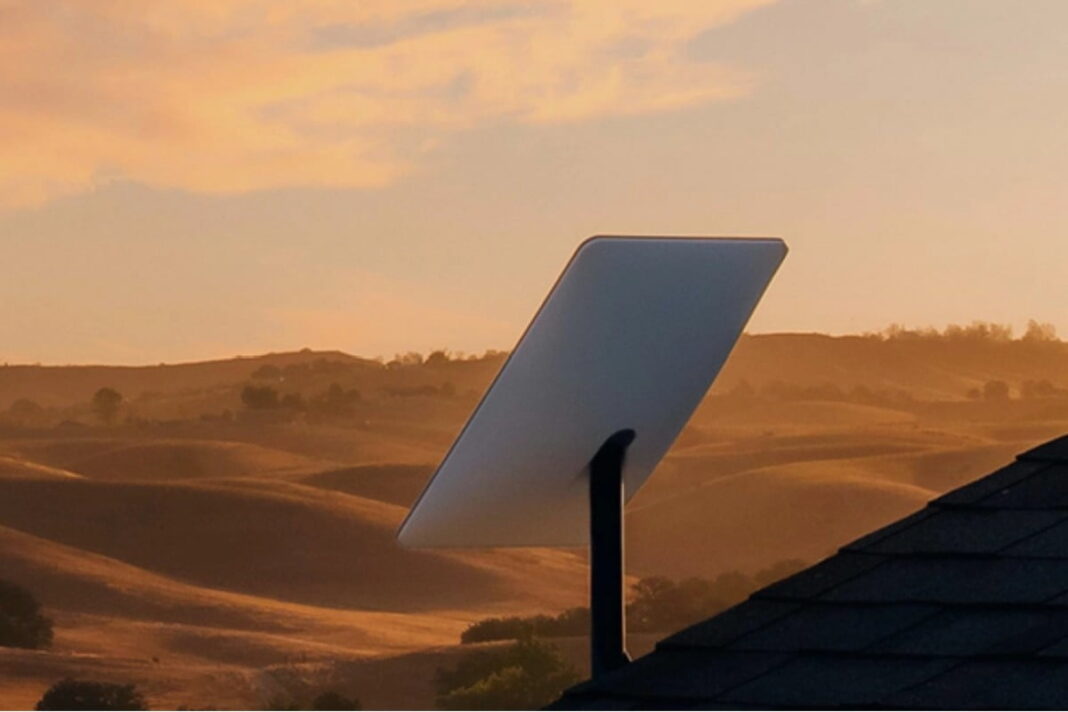 Satellite dish on roof at sunset with hills.