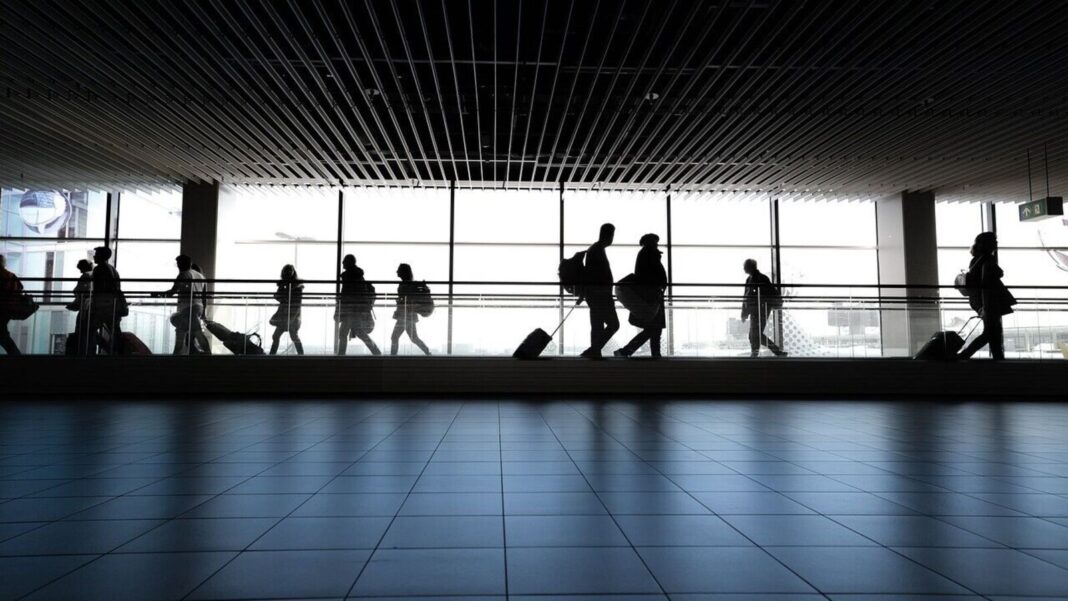 Silhouettes of people walking in airport terminal.