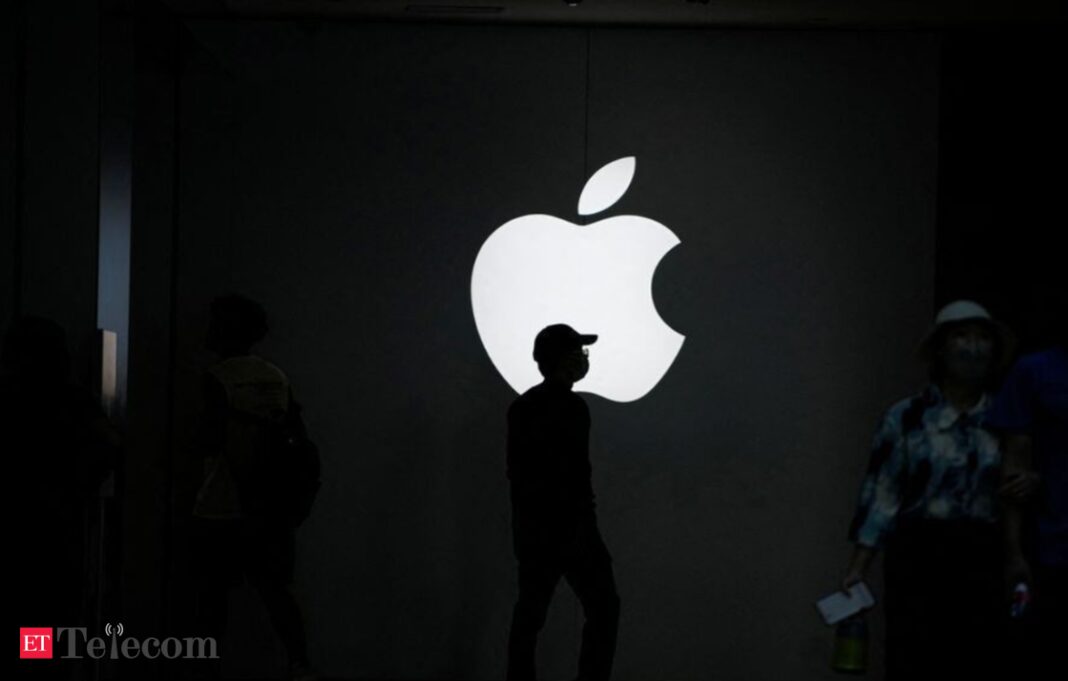 Silhouetted people by glowing Apple logo