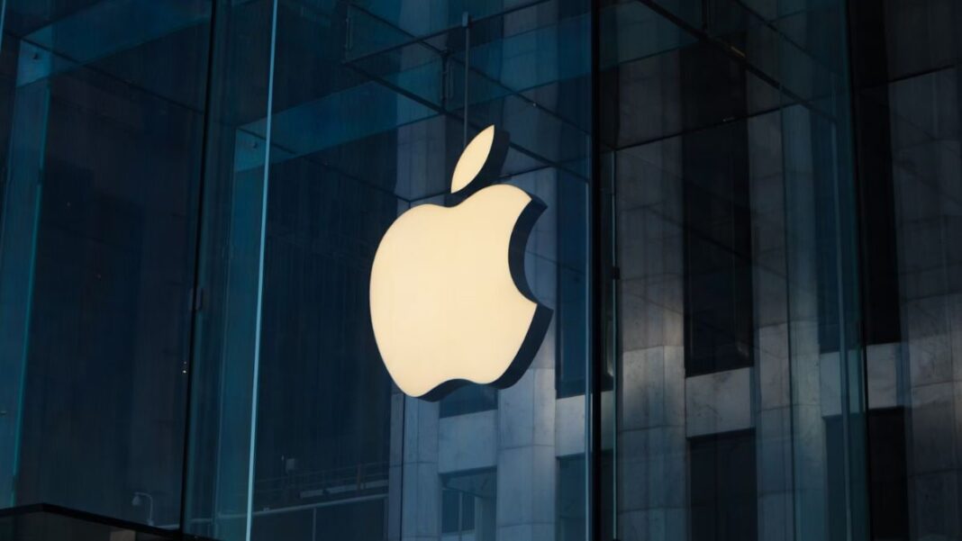 Apple logo on glass storefront at dusk.