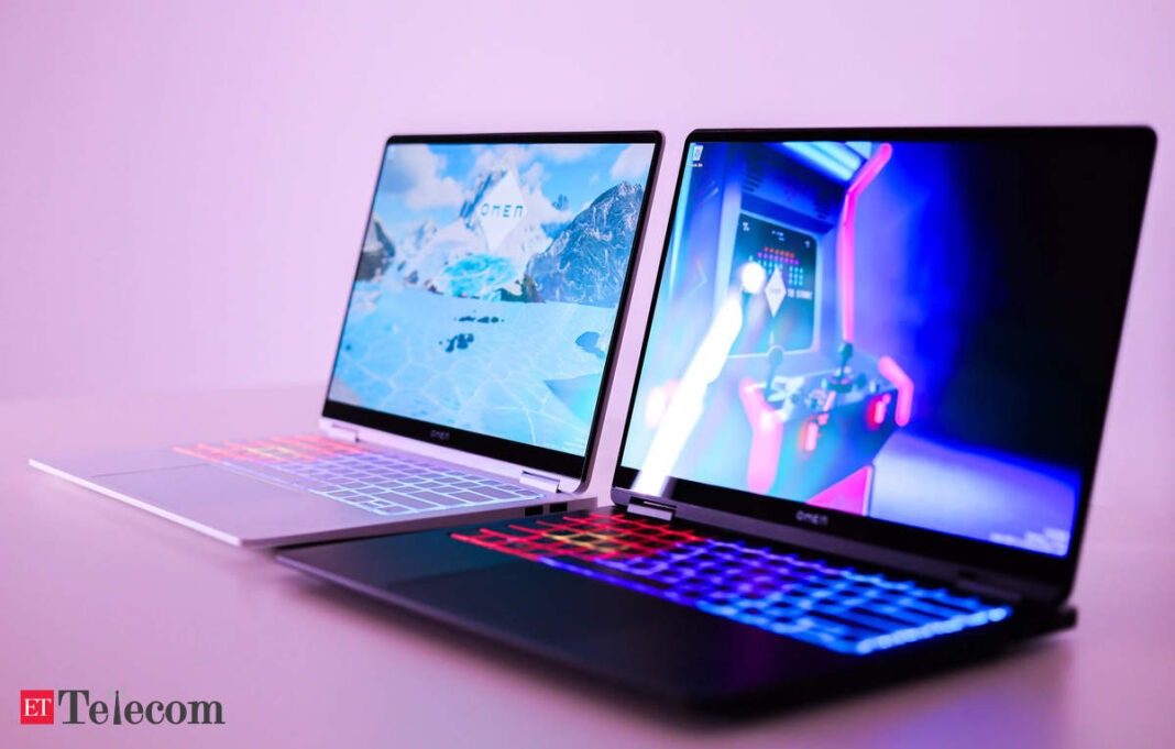 Two open laptops with illuminated keyboards on pink background.