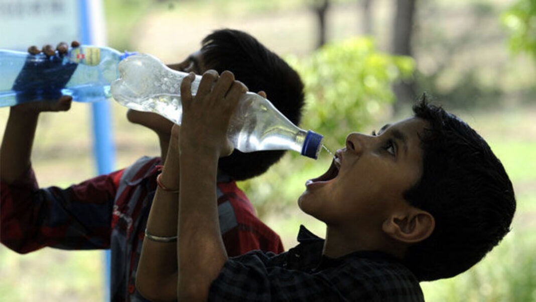 Boys drinking water from bottle outdoors.