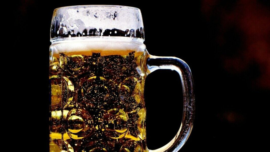 Frosted beer mug with amber liquid on dark background.