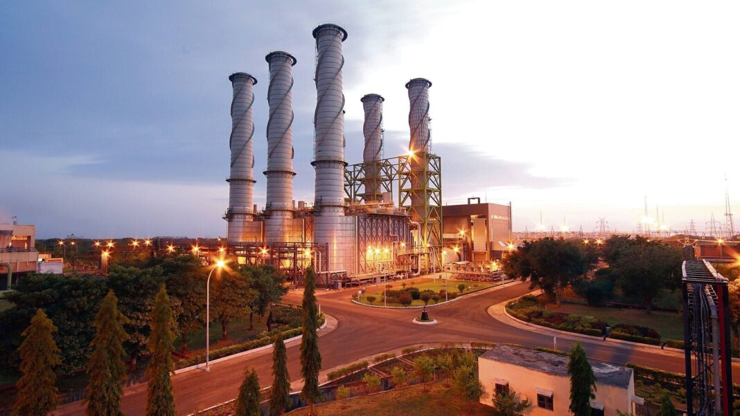 Industrial power plant at twilight with illuminated lights.