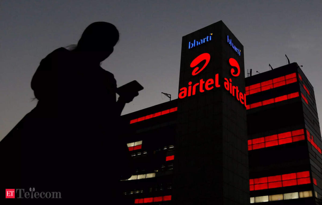 Silhouette using mobile, Airtel building at dusk.