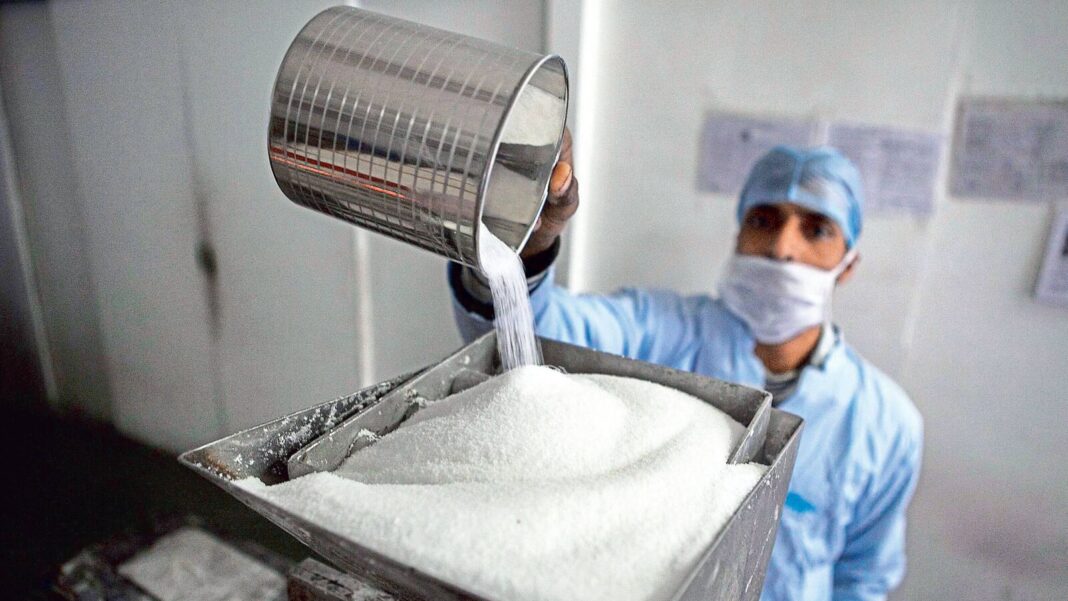 Worker pouring sugar at processing plant.