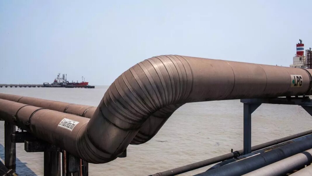 Industrial pipeline near water with ship in background