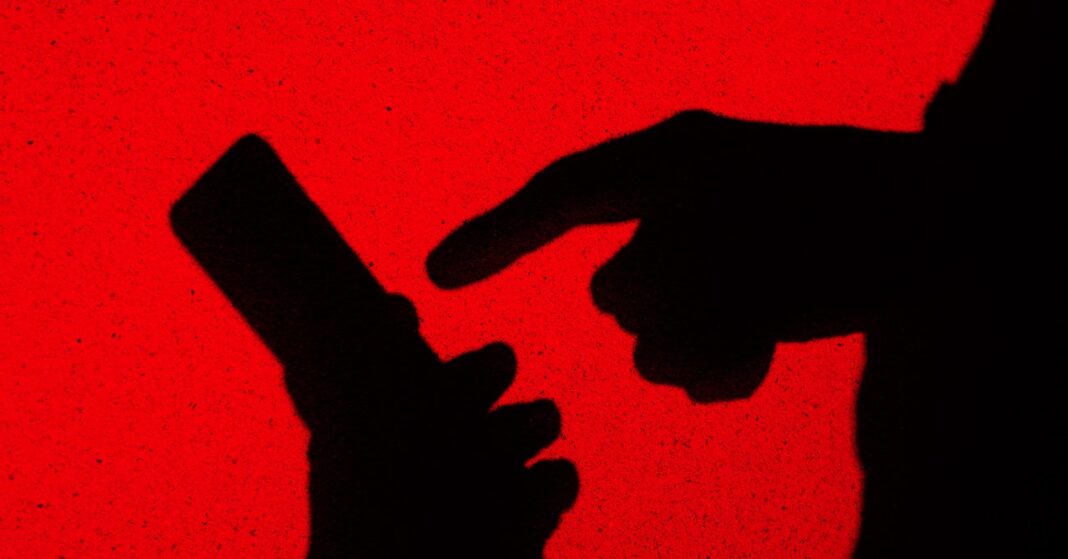 Silhouette of finger pointing at smartphone on red background.