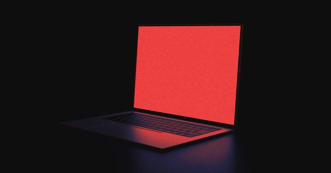 Illuminated laptop with red screen in dark setting.