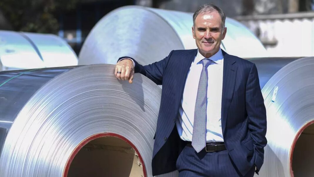 Man in suit posing with industrial metal coils.