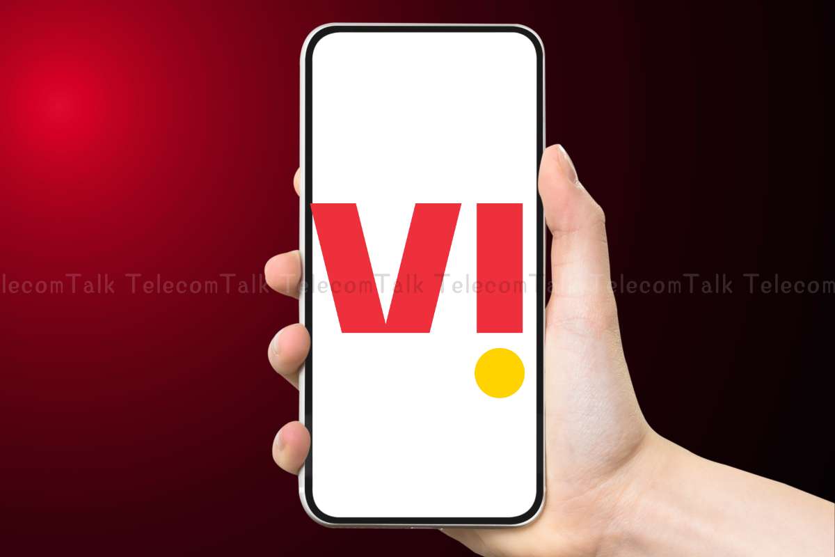 Hand holding smartphone with red and white 'VI' logo.