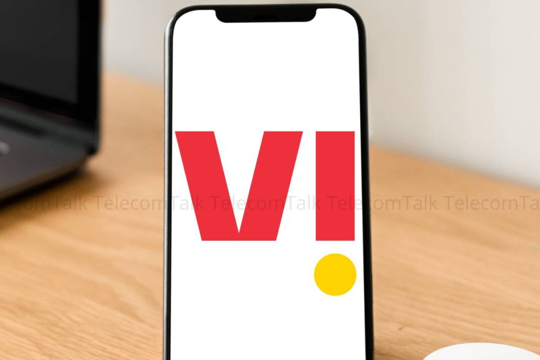 Smartphone screen displaying red 'VI' logo on desk.