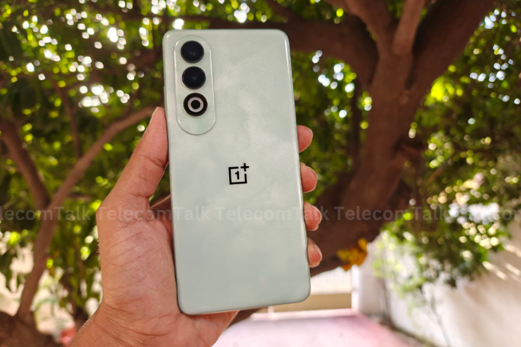 OnePlus smartphone held outdoors with tree background.