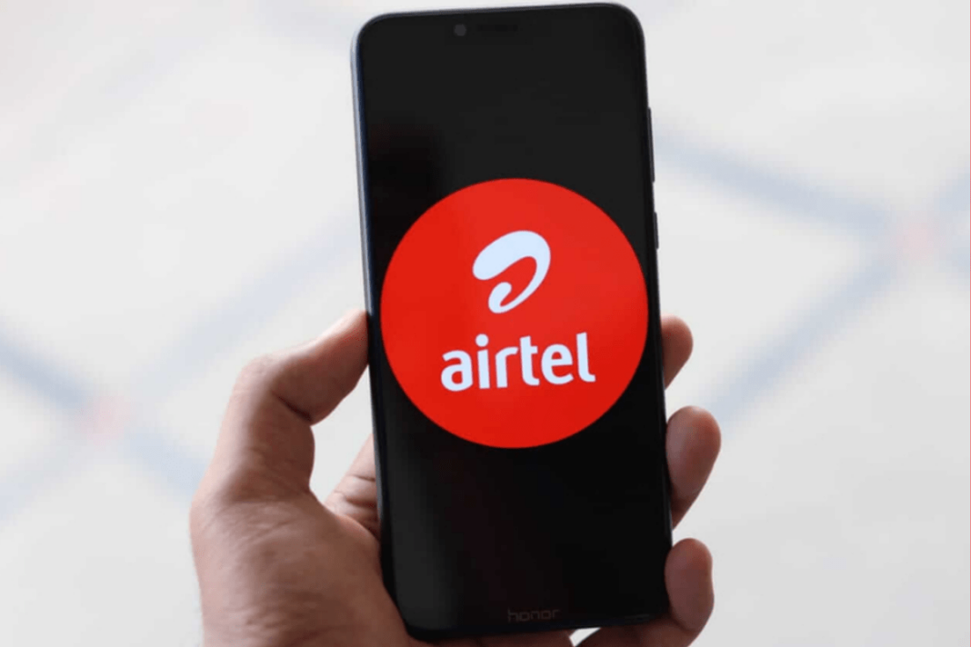 Hand holding phone with Airtel logo on screen.