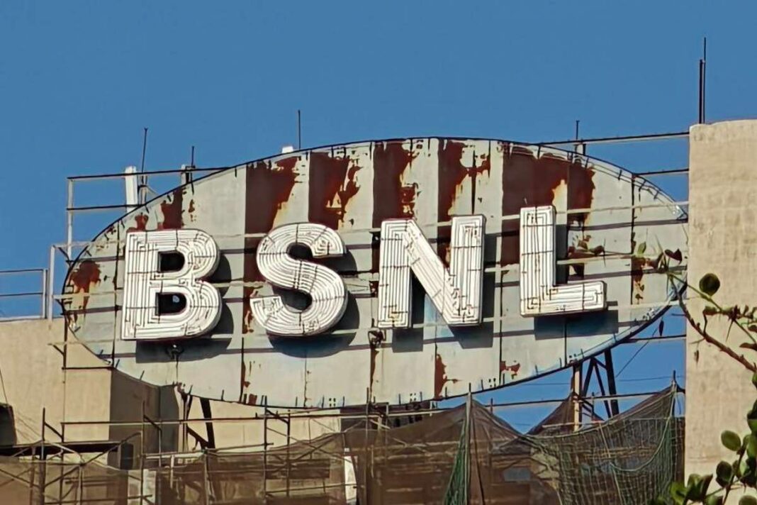 Rusted BSNL signboard on building rooftop.