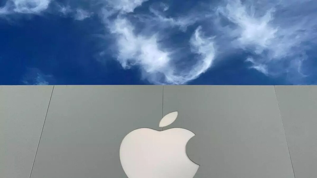 Apple logo against blue sky with clouds.