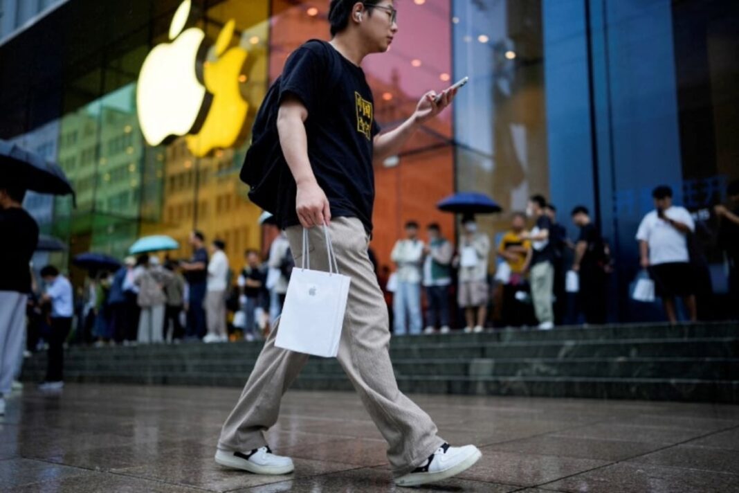 Person walking by Apple store with shopping bag.