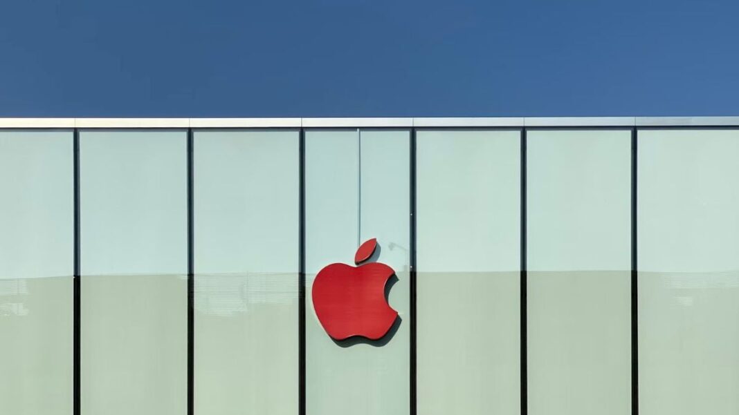 Apple logo on storefront under blue sky.