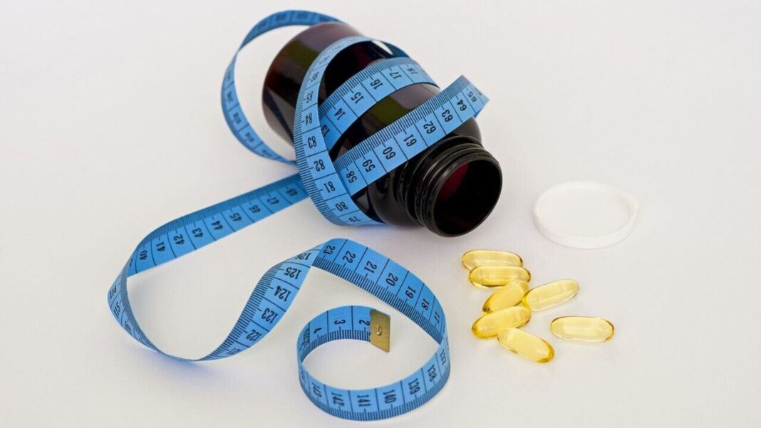 Measuring tape, pill bottle, and nutritional supplements.