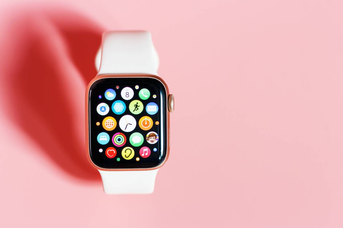 Smartwatch with colorful app icons on pink background.