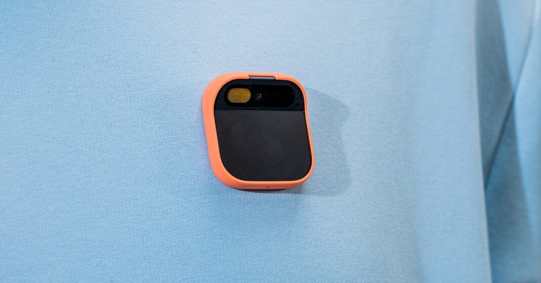 Portable orange-trimmed black camera on blue fabric.