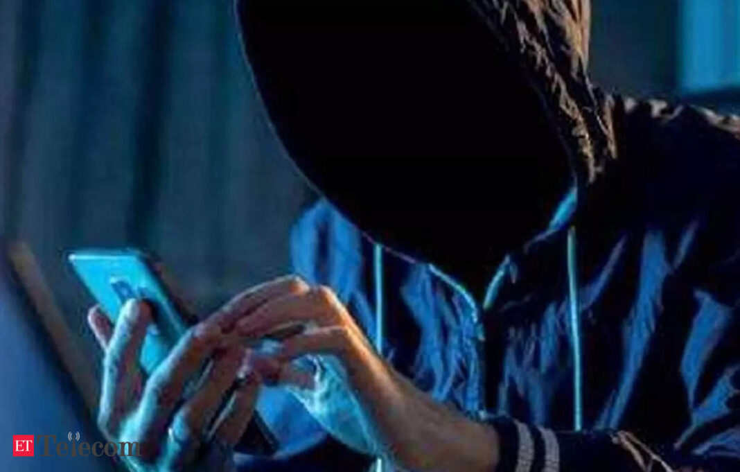 Hooded figure using smartphone in dark room.