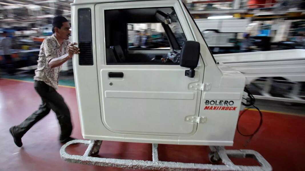 Man pushing car door on assembly line.
