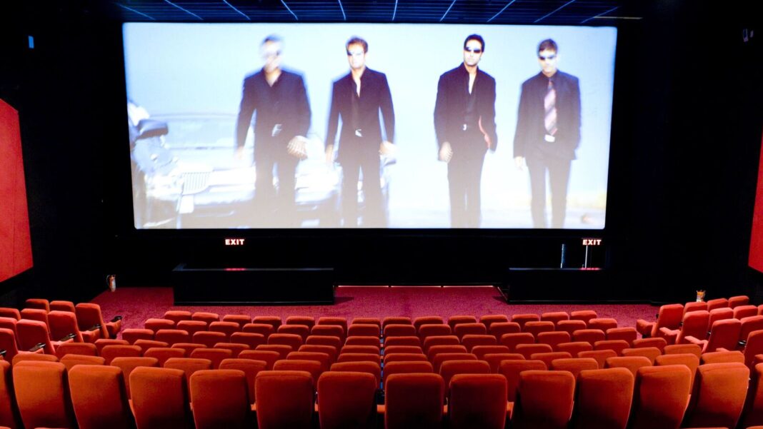 Movie scene projection in empty theater with red seats.