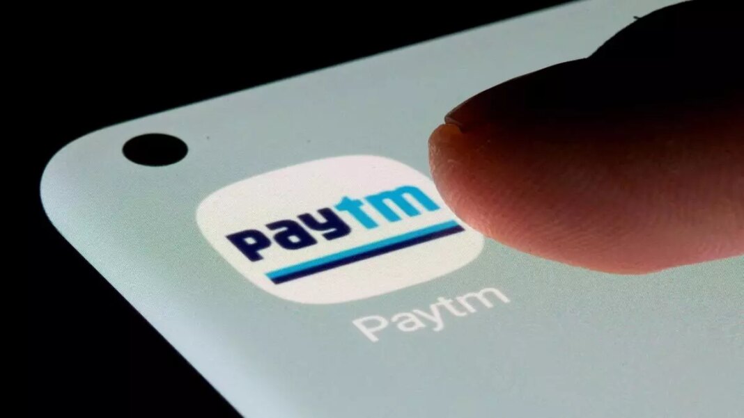 Finger tapping on Paytm logo on smartphone screen.