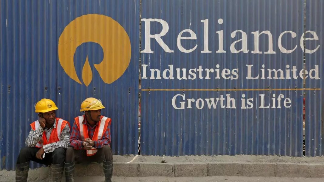 Workers resting by Reliance Industries sign.