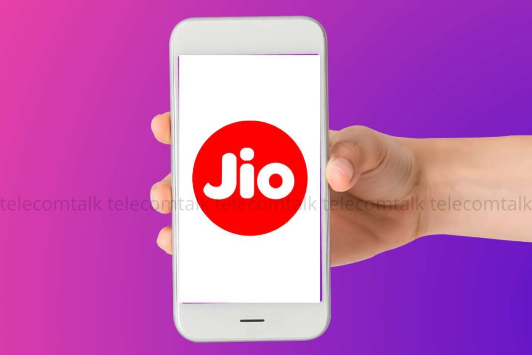 Hand holding smartphone with Jio logo on screen.