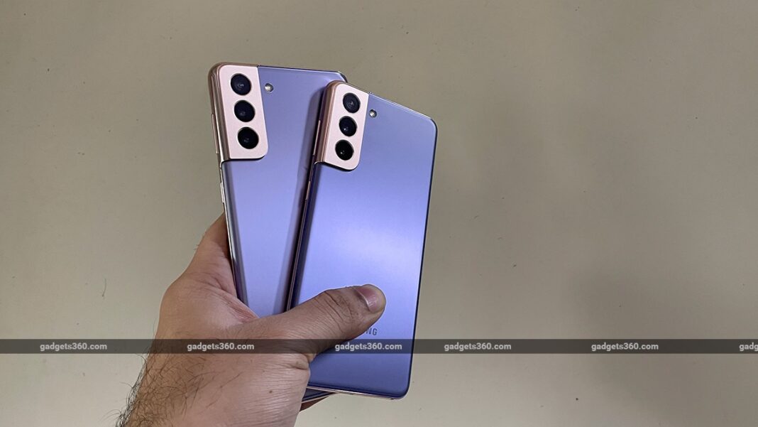 Hand holding two modern smartphones with triple cameras.
