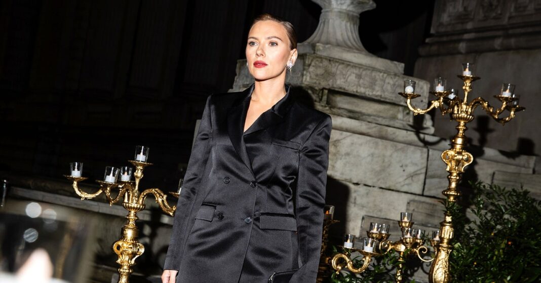 Woman in elegant black blazer at night event.