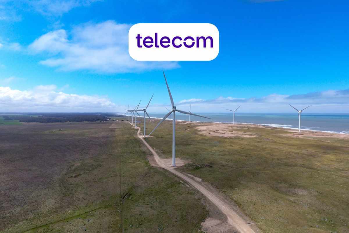 Wind turbines by the coast with "telecom" sign.