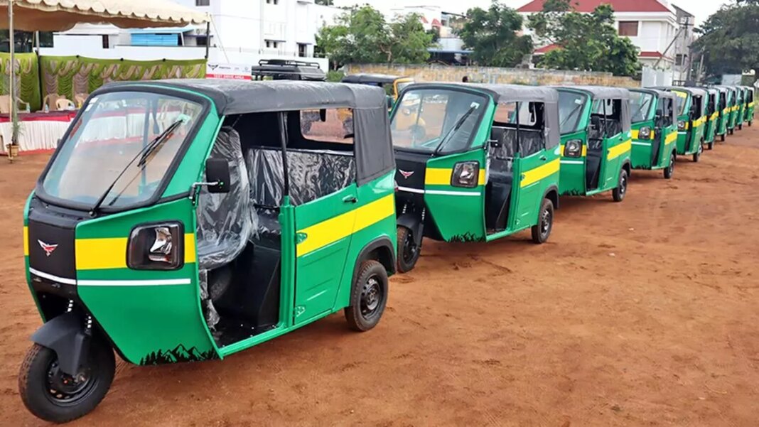 Row of parked green auto rickshaws.