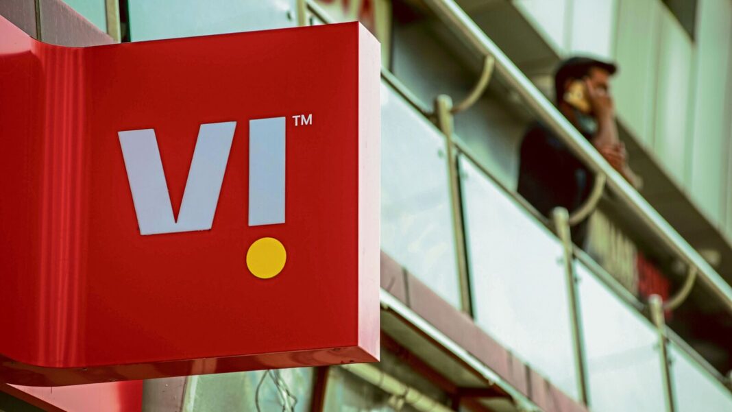Red VI logo sign, person on phone in background.