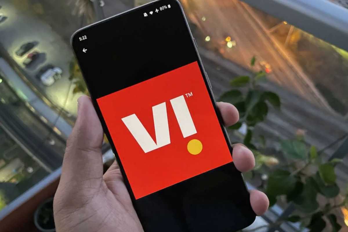 Hand holding smartphone with red logo on screen.