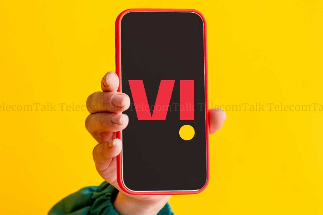 Hand holding smartphone with red V logo on screen.