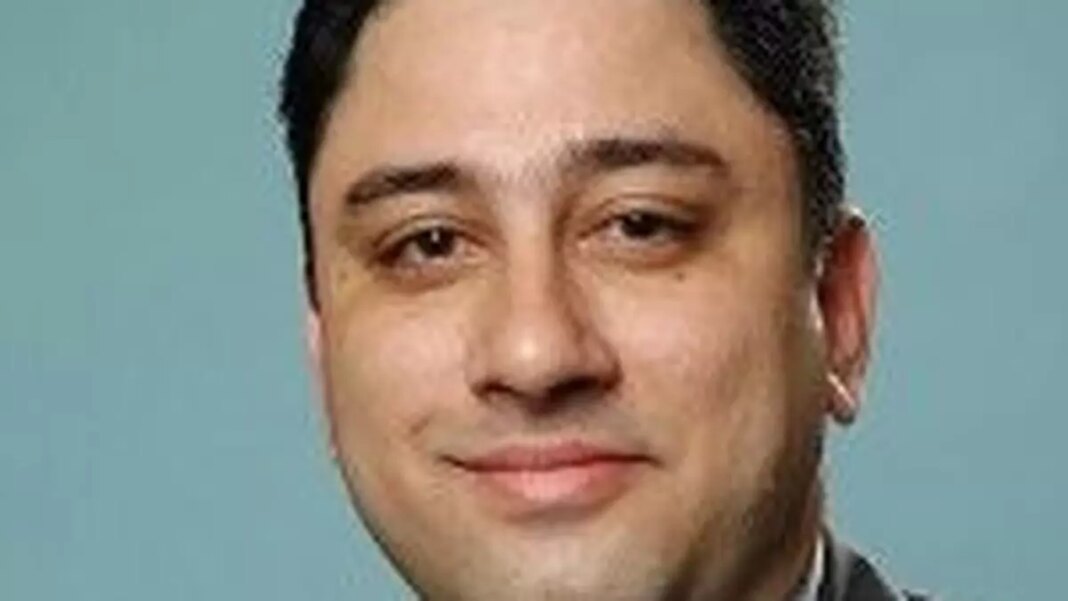 Man smiling, professional headshot, blurred background.