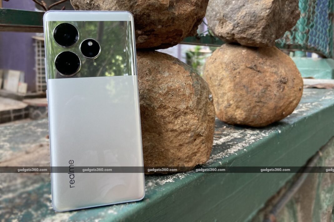 Smartphone with triple cameras on rocky ledge.