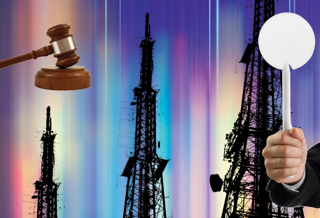 Gavel, hand holding sign, broadcast towers, colorful background.