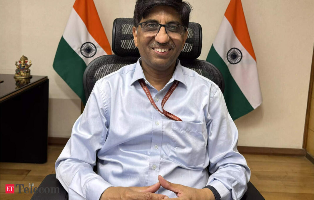 Man smiling in office with Indian flags.