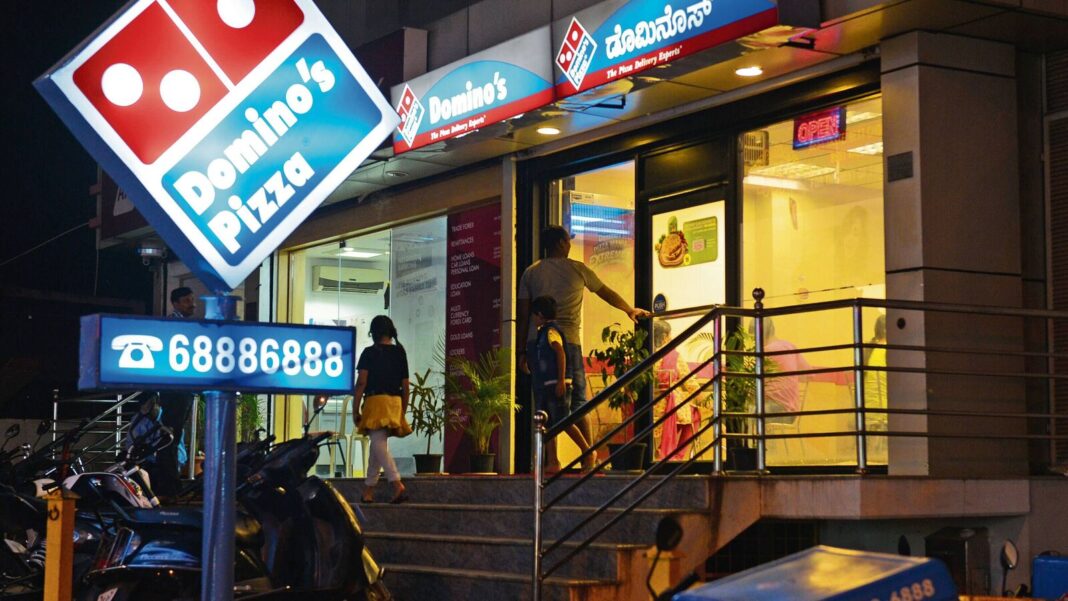 Domino's Pizza storefront with customers at night.