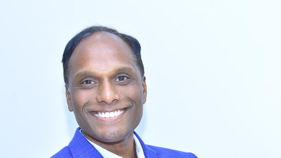 Man smiling in blue suit on white background.