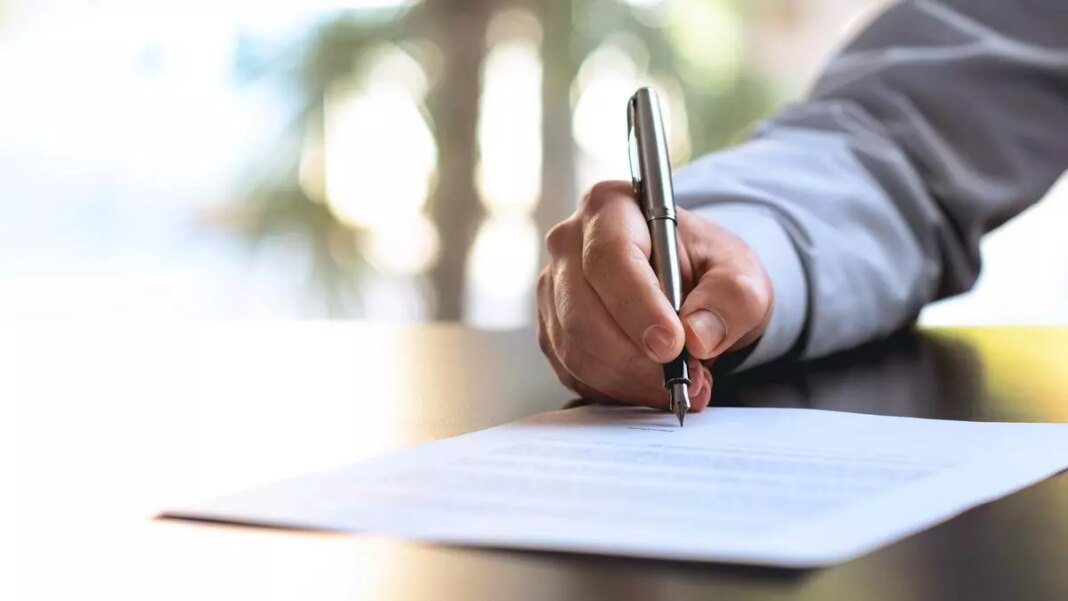Person signing document with pen, close-up